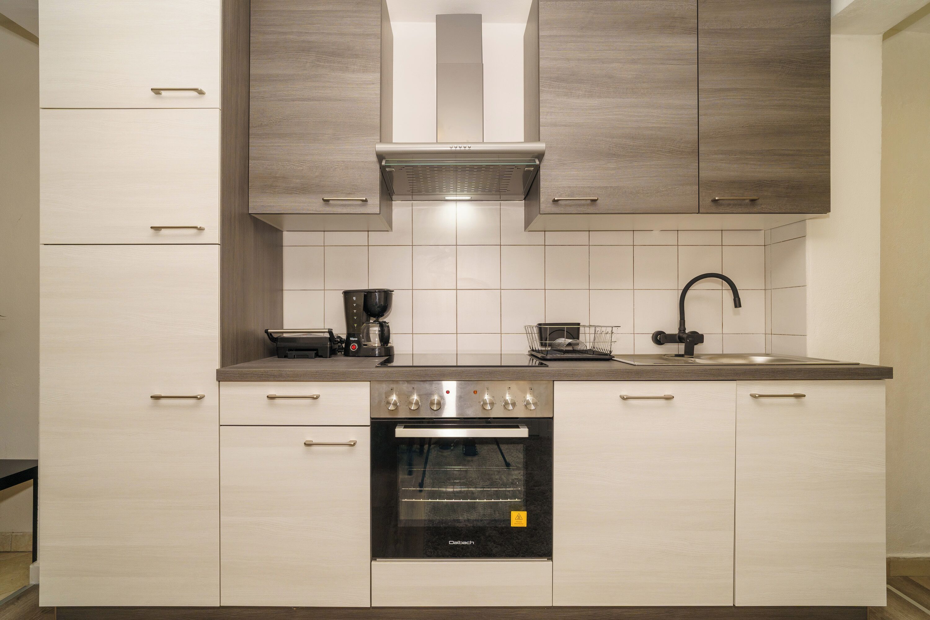A kitchen with a built-in oven, a coffee maker, and a sink.