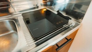 Et køkken med en integreret induktionskogeplade, en stålvask og et træskab.