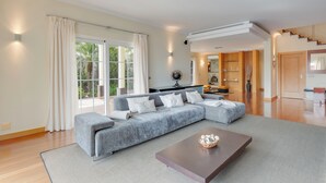 Un salon moderne avec un canapé d’angle gris, une table basse et une vue sur l’extérieur.