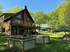 Una cabaña grande de madera con balcón, mobiliario exterior y un jardín cuidado.