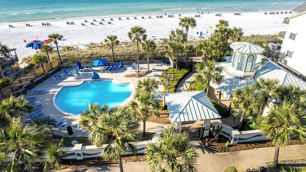 Een resort met een zwembad, strand en palmbomen.