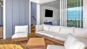 A modern living area with a white sofa, wicker chairs, and a wooden coffee table. - SeaView Rooftop-Steps To Beach w/Parking/Elevator! (Carolina Beach)