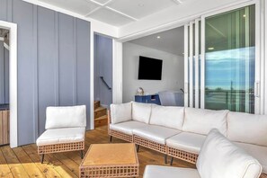 A modern living area with a white sofa, wicker chairs, and a wooden coffee table. - SeaView Rooftop-Steps To Beach w/Parking/Elevator! (Carolina Beach)