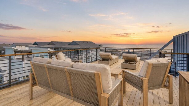A wooden deck with outdoor seating and a view of the ocean at sunset. - SeaView Rooftop-Steps To Beach w/Parking/Elevator! (Carolina Beach)