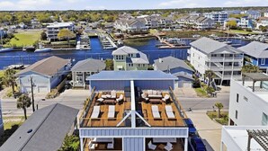 A multi-story building with a rooftop deck, a marina in the background, and residential buildings nearby. - SeaView Rooftop-Steps To Beach w/Parking/Elevator! (Carolina Beach)