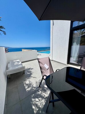 A balcony with a view of the sea, a pool, and a chair. - Sunny Coast - Panoramic View & Pool (Sarandë)