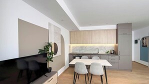 Une cuisine moderne avec un coin repas, un téléviseur et une plante.
