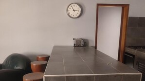 A modern kitchen with a tiled countertop, a built-in oven, and a clock on the wall.