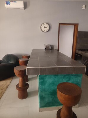 A modern kitchen with a tiled countertop, a built-in oven, and a clock on the wall.