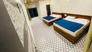 Ein Hotelzimmer mit zwei Betten, einem Deckenventilator, einem Fliesenboden und einer Tür, die auf einen Balkon führt.