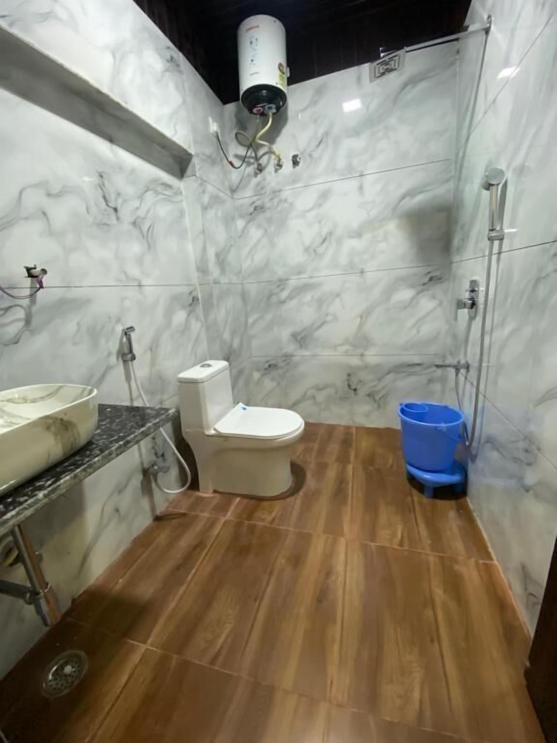 Un baño con pared de mármol, inodoro, lavamanos y ducha.