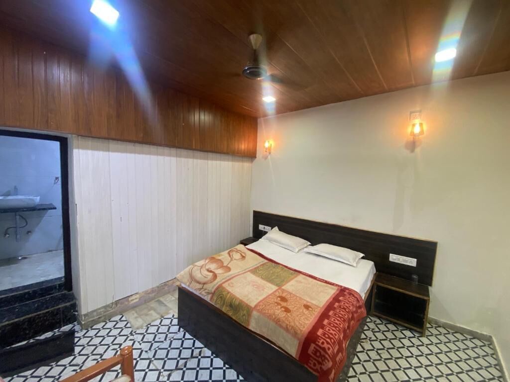 Ein Schlafzimmer mit einem Bett, Holzboden, Fliesenboden und einem kleinen Nachttisch.