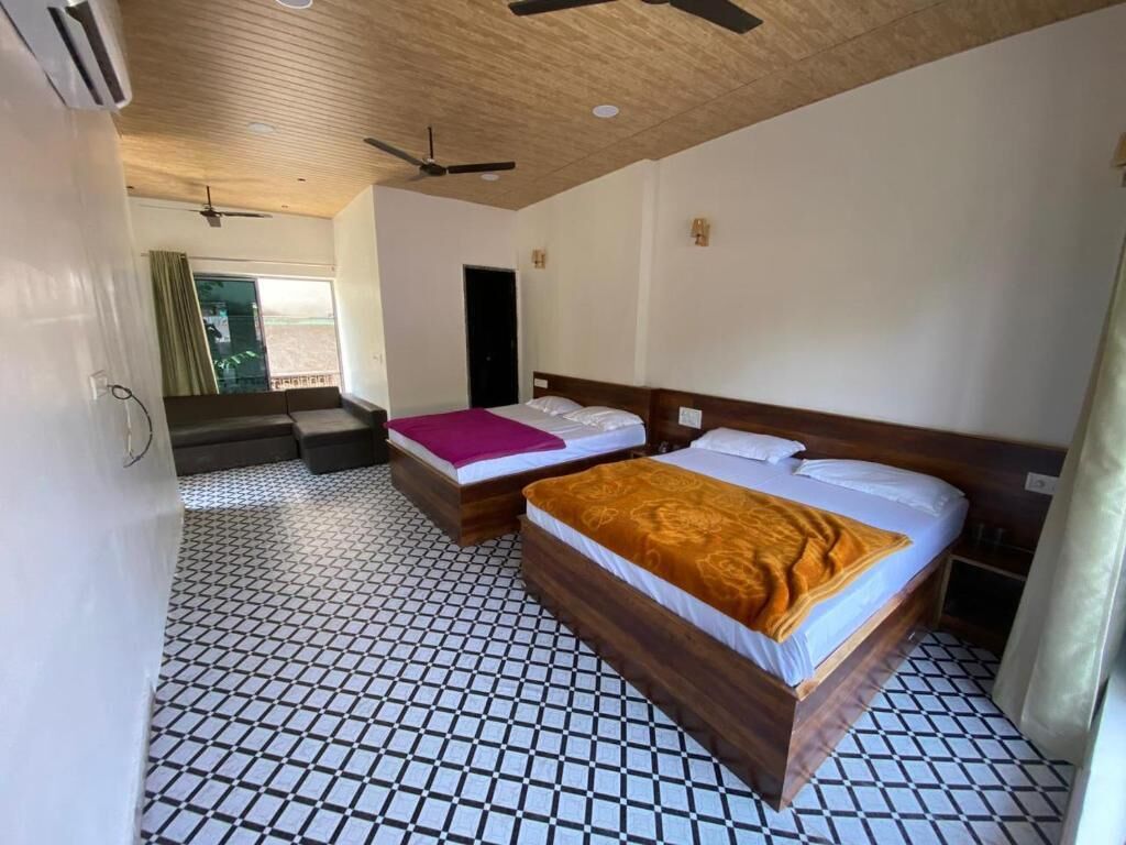 A hotel room with two beds, a wooden ceiling, a tiled floor, and a balcony.