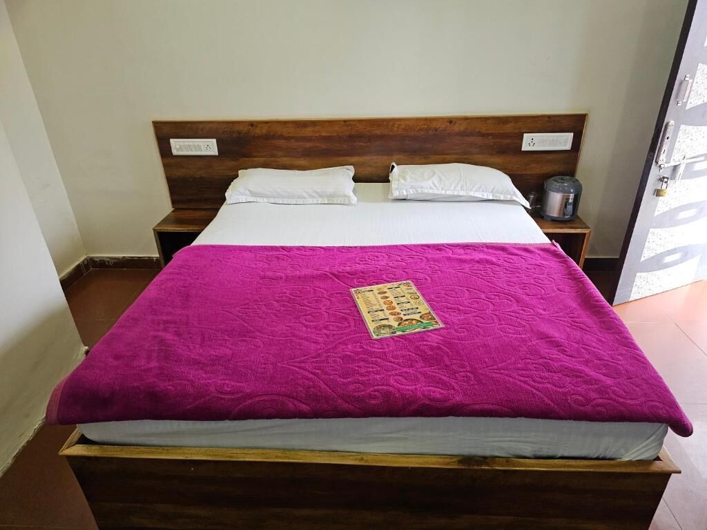 A single bed with a wooden headboard, white pillows, and a pink blanket.
