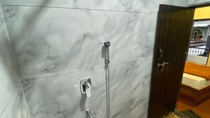 Ein Badezimmer mit Marmorwänden, einer Dusche, einer Toilette und Holzboden.