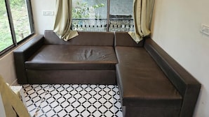 Ein Zimmer mit einem schwarz-weißen Fußboden, einem braunen Sofa und einem Fenster mit Vorhängen.