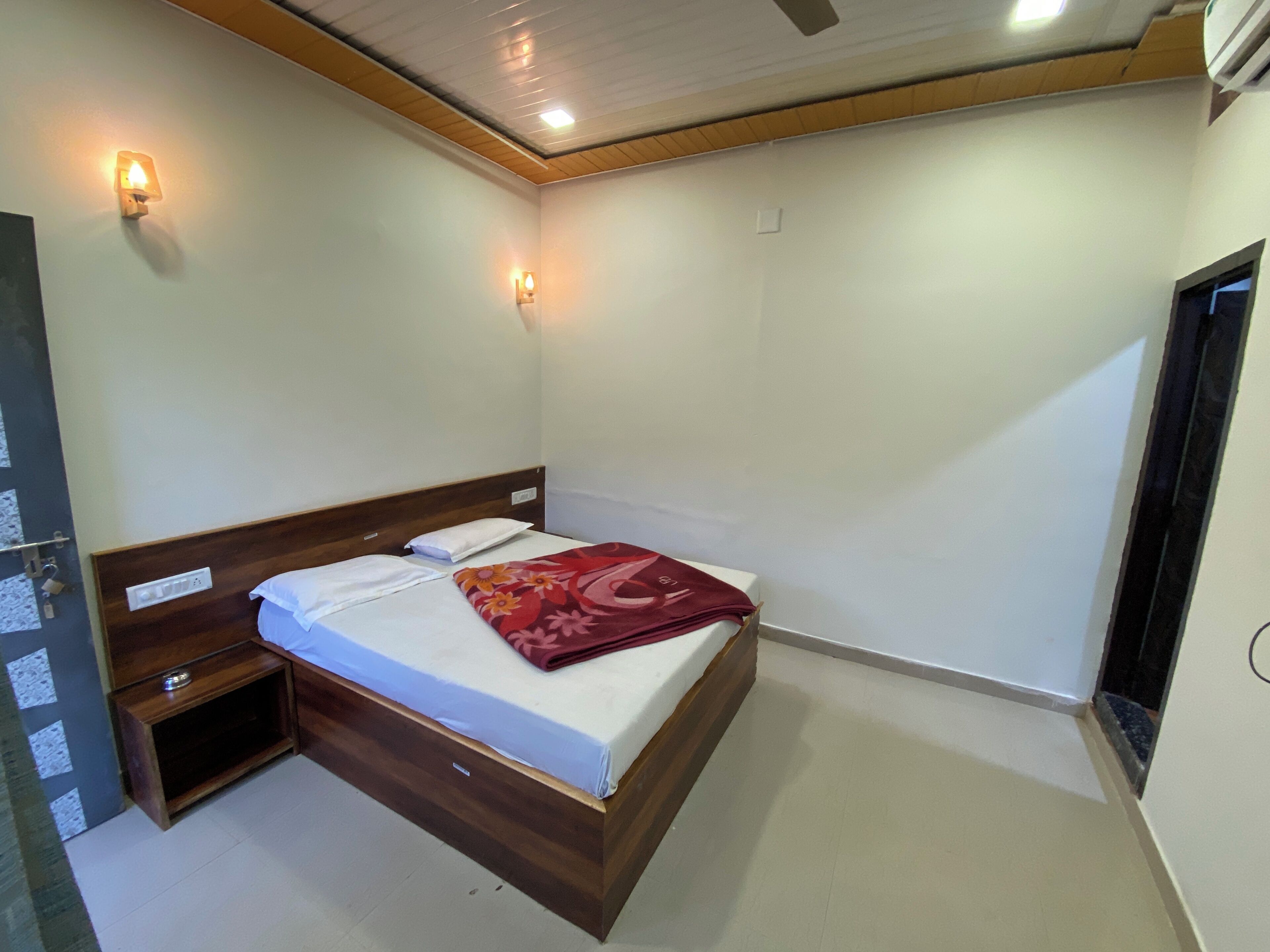 A single bed with a wooden headboard, a bedside table, and a wall-mounted light fixture.