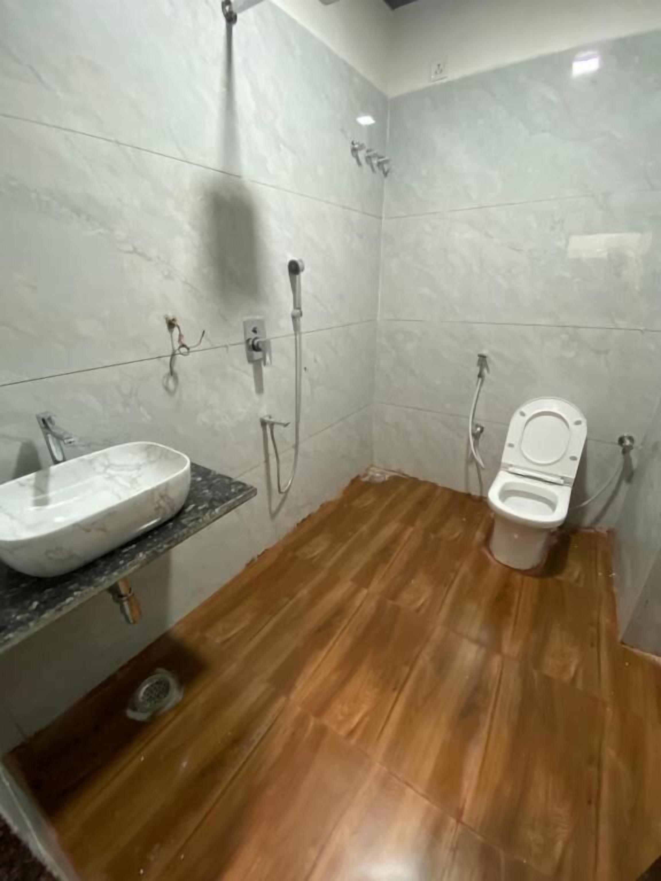 A bathroom with a marble sink, wooden floor, and a toilet.