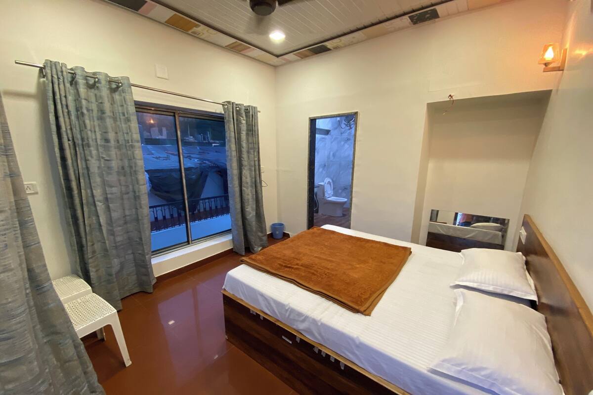 Quarto com cama, janela, cadeira e uma pequena mesa.