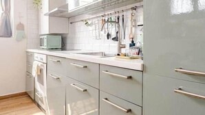 A kitchen with light-colored cabinets, a microwave, and hanging utensils. - Historic Apartment near center + Free Parking (Como)