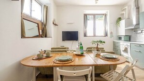 A dining area with a wooden table, chairs, a TV, and a kitchen in the background. - Historic Apartment near center + Free Parking (Como)