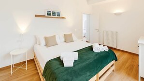 A hotel room with a bed, a small side table, a radiator, and a mirror. - Historic Apartment near center + Free Parking (Como)