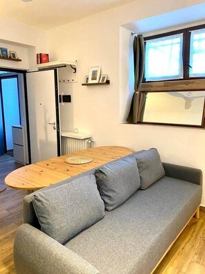 A modern living room with a grey sofa, wooden coffee table, and a window with curtains. - Historic Apartment near center + Free Parking (Como)
