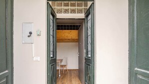 A narrow hallway with a wooden floor, a white chair, and a small table. - Historic Apartment near center + Free Parking (Como)