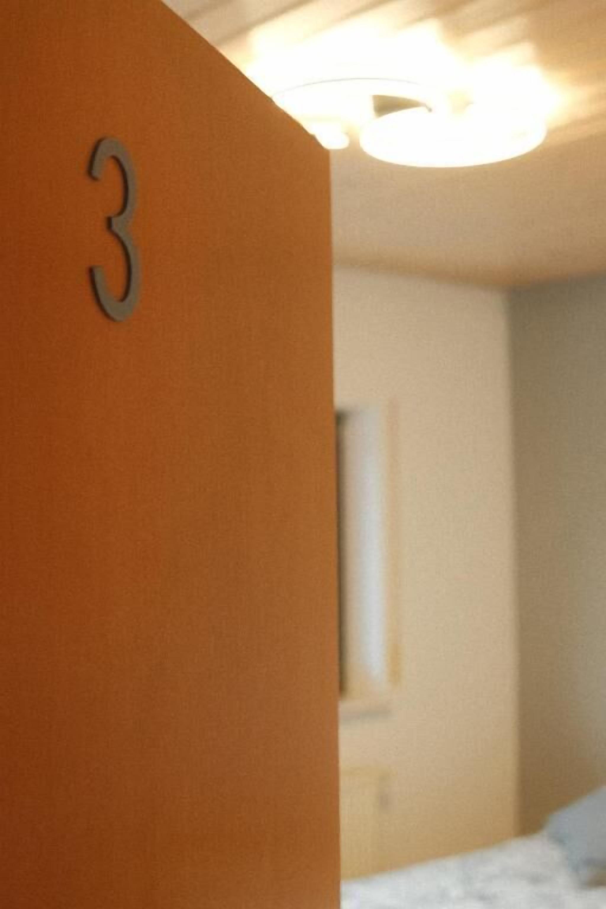 Una habitación con el número 3 en la pared, una cama y una lámpara en el techo.