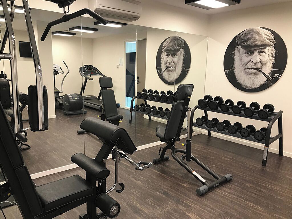 Une salle de sport équipée de machines d’exercice, d’un tapis de course et d’un porte-haltères.