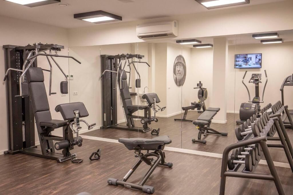 A gym with various exercise equipment, a mirror, and a television screen.