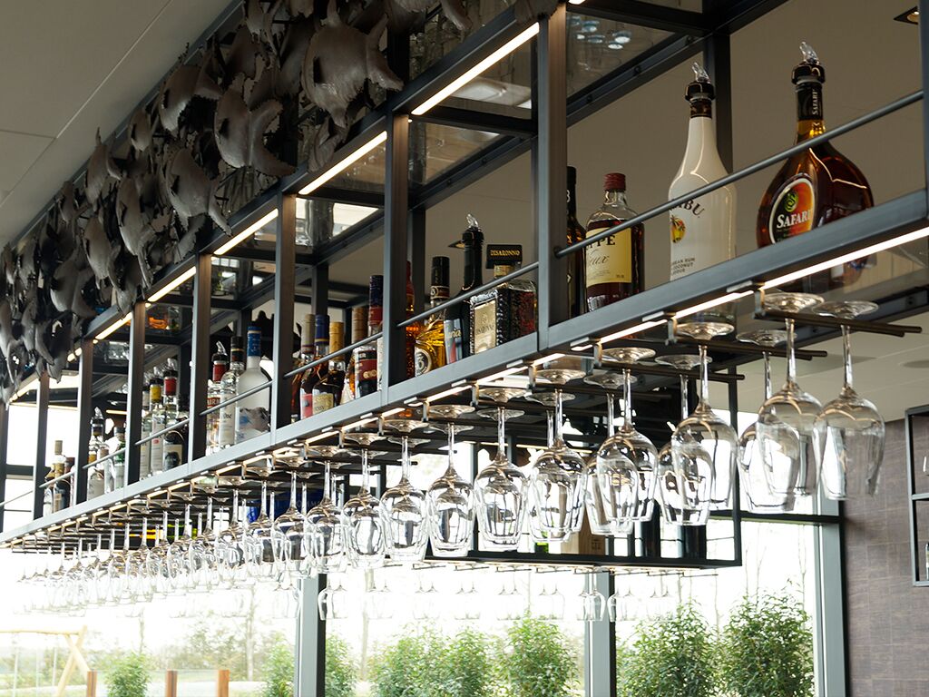 A bar area with shelves of liquor bottles and hanging wine glasses.