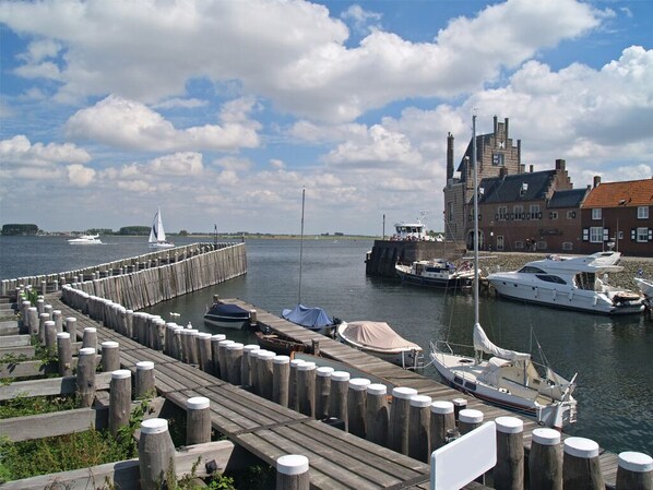 A waterfront dock with boats, a wooden pier, and a historic building with a red roof.