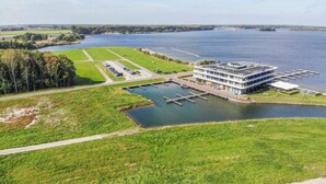 Hotel aan de rivier met een steiger, parkeerplaats en gazon.