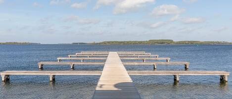 A wooden pier extending into calm water with a clear sky above.