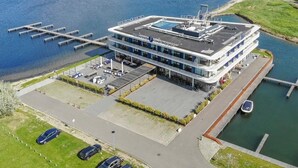 Een modern hotel met een dakterraszwembad, een jachthaven en een parkeerplaats.