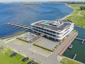 A modern hotel with a rooftop pool, a marina, and a parking area.