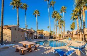 A pool area with lounge chairs and a table, surrounded by tall palm trees. - Fountain Hills Gem >Pool, Balcony & Mountain View (Fountain Hills)