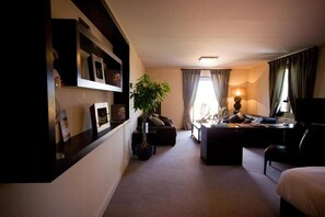 A hotel room with a sofa, a desk, a TV, a lamp, a potted plant, and a bed. - Le daya Hôtel & Spa  (Roquebrune-sur-Argens)