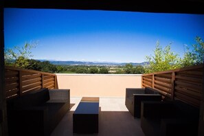 A rooftop terrace with wicker furniture, a flat surface, and a scenic view of distant mountains and greenery. - Le daya Hôtel & Spa  (Roquebrune-sur-Argens)