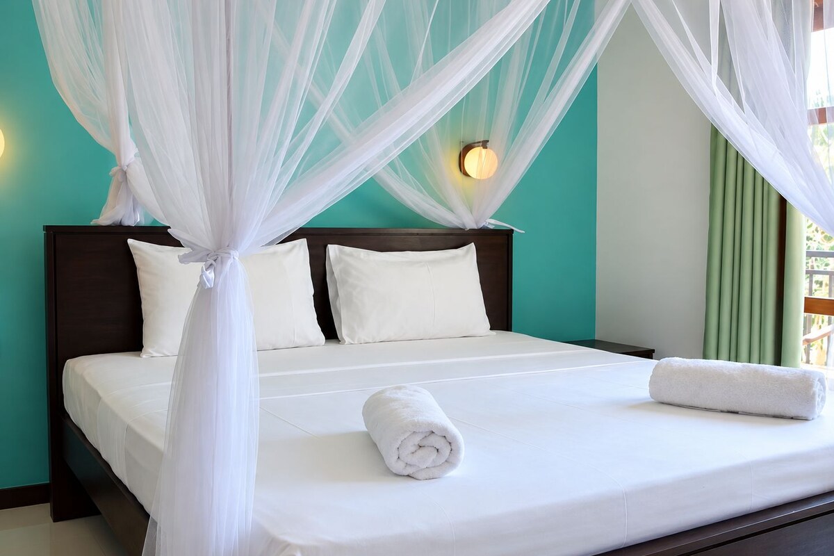 A bed with a canopy, pillows, and a rolled towel.