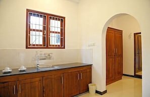 A kitchen with a wooden countertop, a window with bars, and a wooden cabinet.