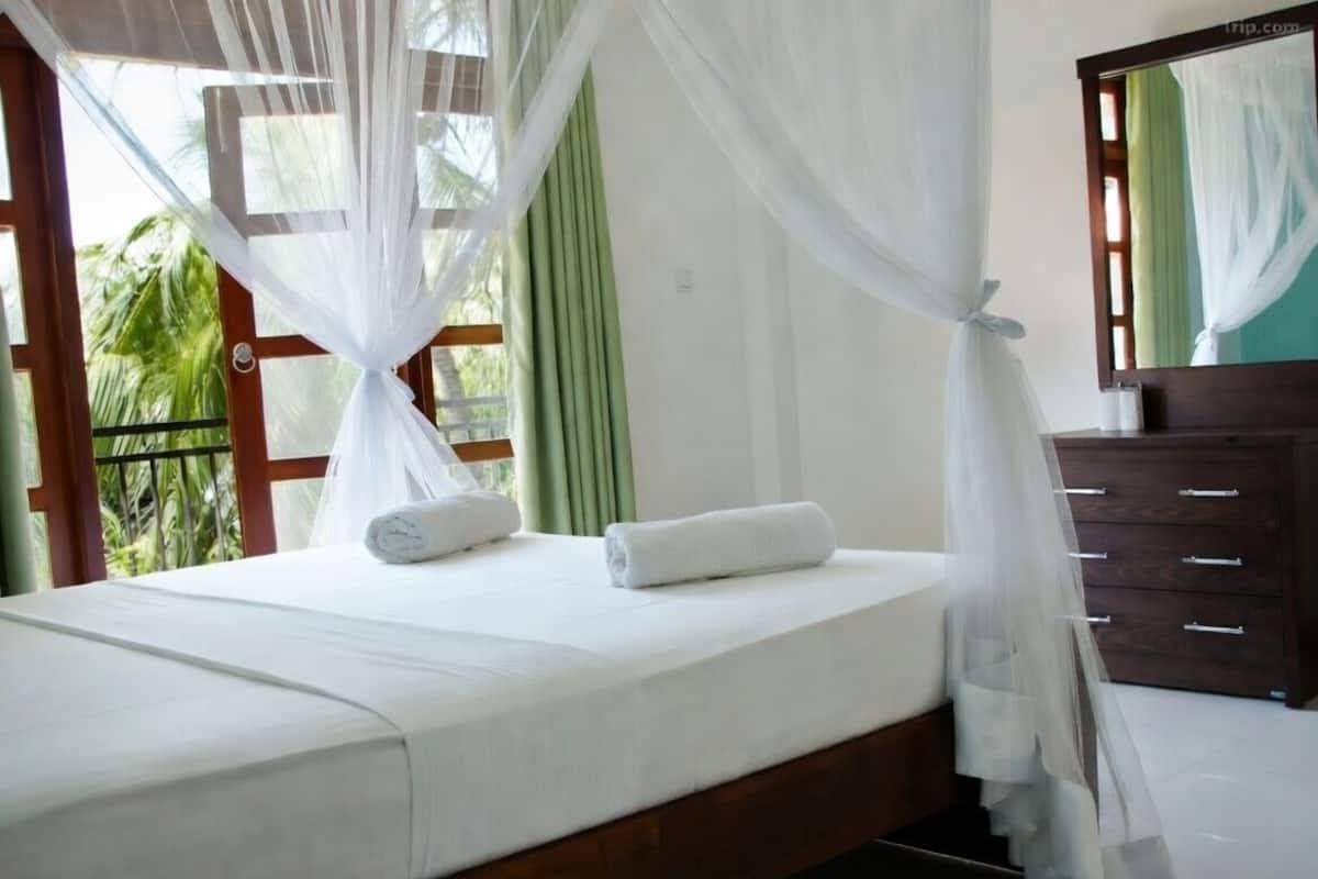 A bed with white bedding, a wooden headboard, and a canopy.