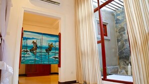 A hallway with a painting, a window with curtains, and a stone wall. - Villa Estuary (Bentota)
