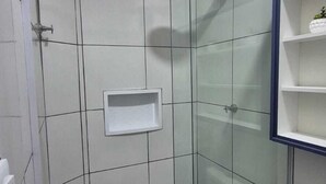 A small, enclosed shower area with a glass door, a white sink, and a toilet. - Residencial New Stilo (Aracati)