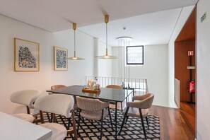 A dining area with a black table, six chairs, two pendant lights, and framed artwork on the wall. - Premium 2BR Duplex Douro River View (Vila Nova de Gaia)