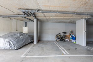 A parking garage with a covered vehicle, a bicycle, and a fire extinguisher. - Premium 2BR Duplex Douro River View (Vila Nova de Gaia)