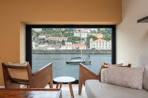 Ein Zimmer mit großem Fenster und Blick auf einen Hafen, ein Segelboot und Gebäude am Wasser.