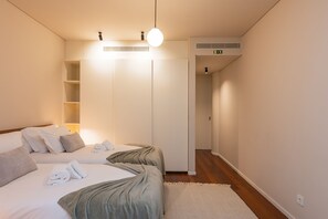 A hotel room with a bed, a wardrobe, a bedside table, and a light fixture. - Premium 2BR Duplex Douro River View (Vila Nova de Gaia)