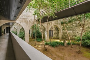 Ein Innenhof mit Bogenwegen, viel Grün und einer modernen Brücke.